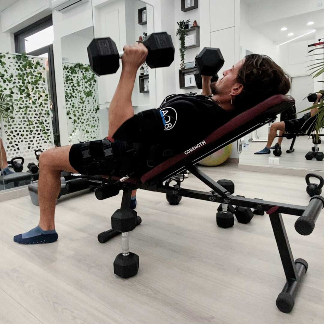 Cliente di Novafit solleva pesi su una panca indossando la tuta EMS.