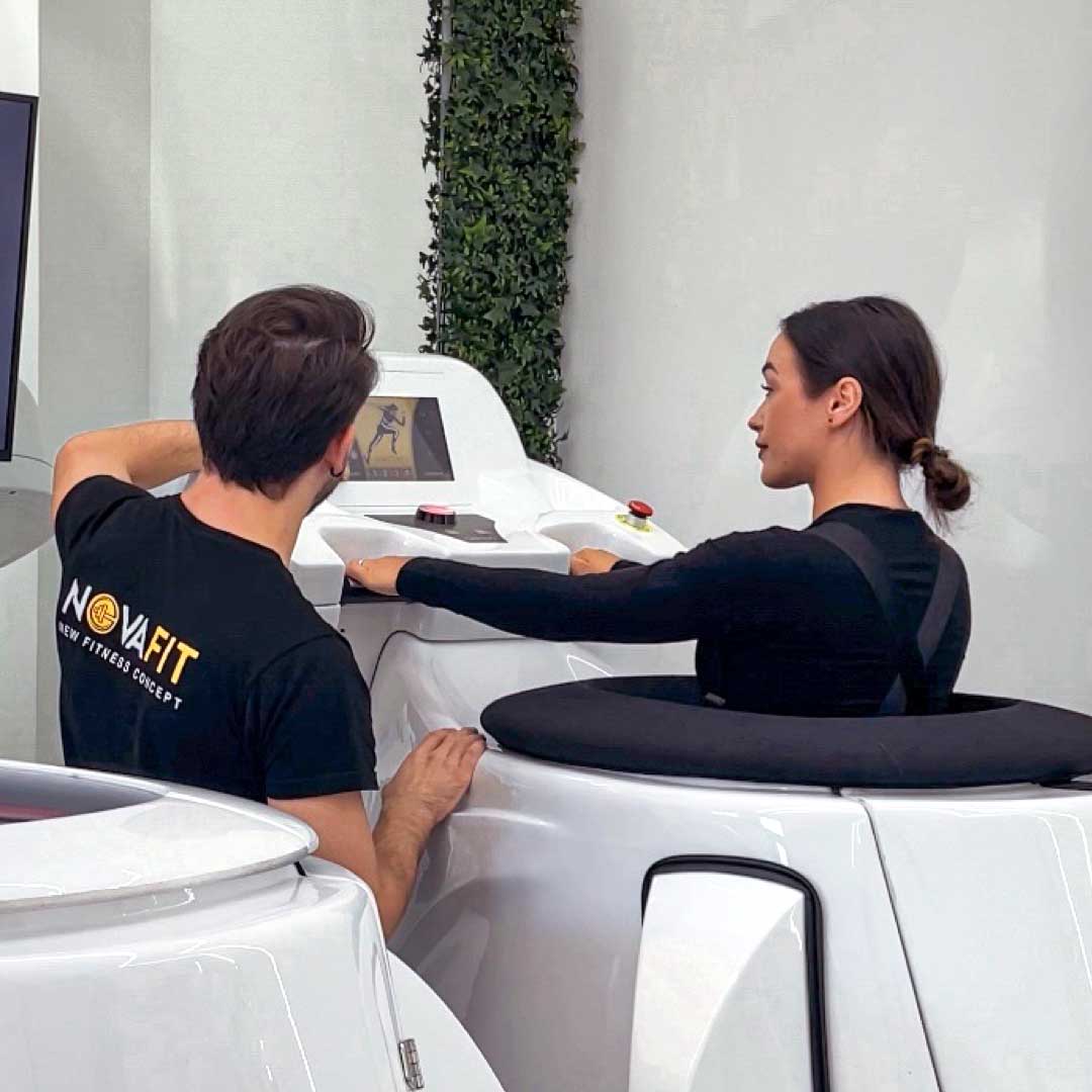 Personal trainer Novafit mostra la tecnologia VACUFIT a una cliente nella palestra a Frattamaggiore.