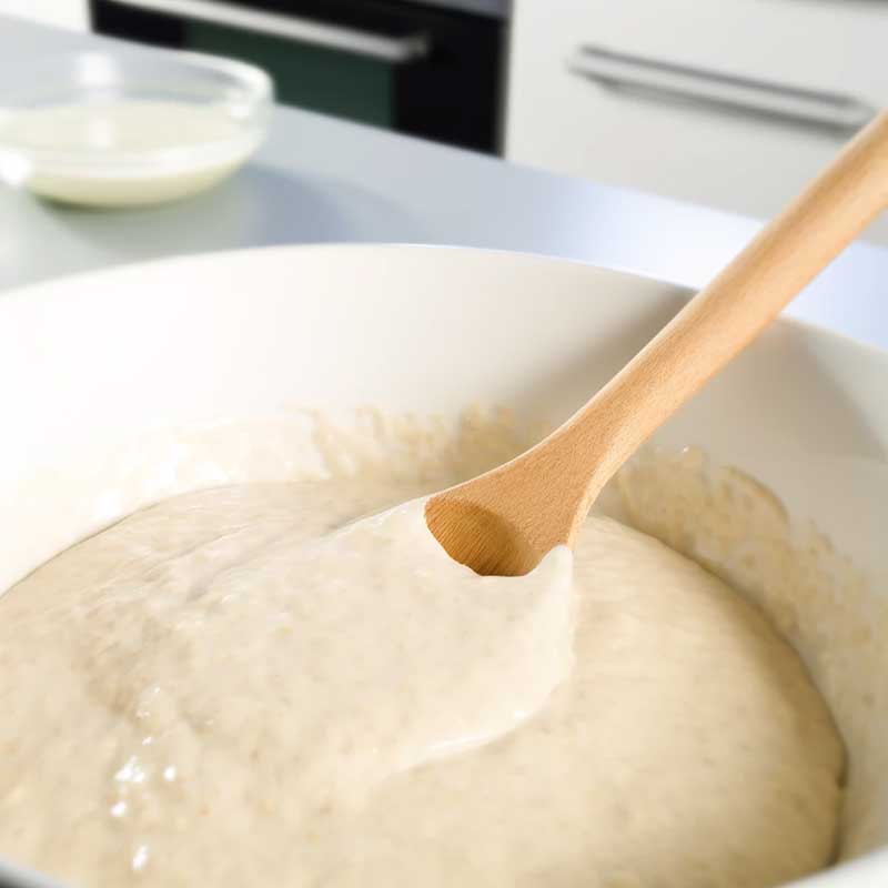 Impasto per pancake proteici in una ciotola, con un cucchiaio di legno, in una cucina moderna e luminosa.