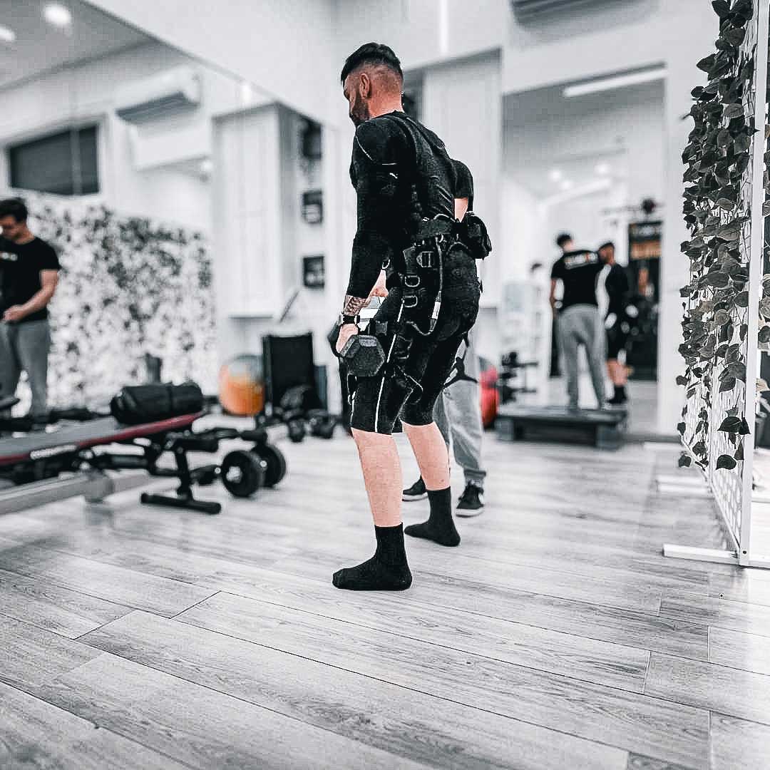 Un personal trainer di NOVAFIT guida un cliente durante una sessione di allenamento EMS.
